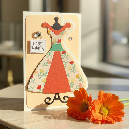 Greeting card with a dress design and flowers on a wooden surface
