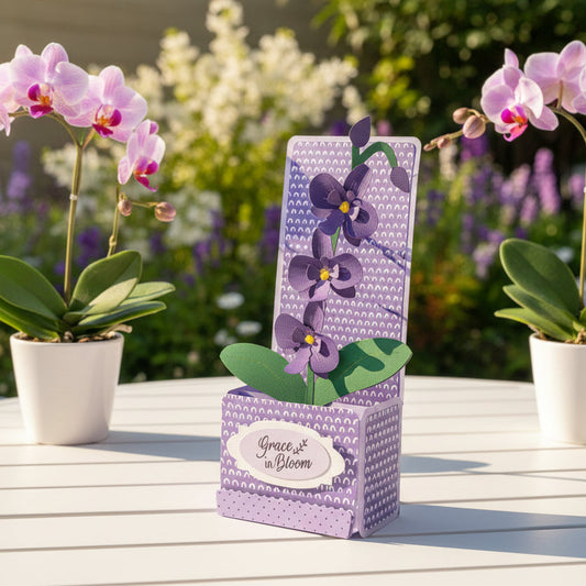 Decorative box card with purple orchid design on a table outdoors