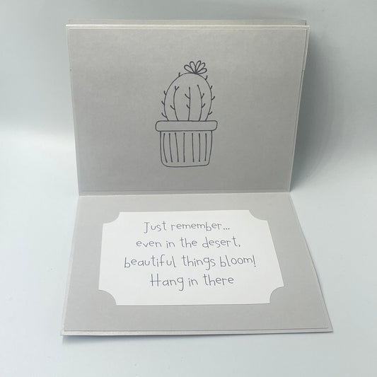 Open card with cactus design and text on a light gray background