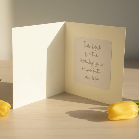 Greeting card with a message on a wooden surface with yellow tulips