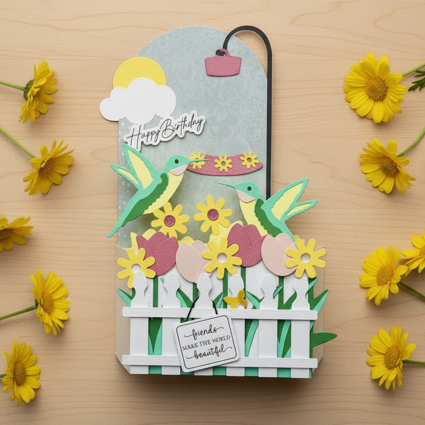Decorative birthday card with hummingbirds, flowers, and a fence on a white background