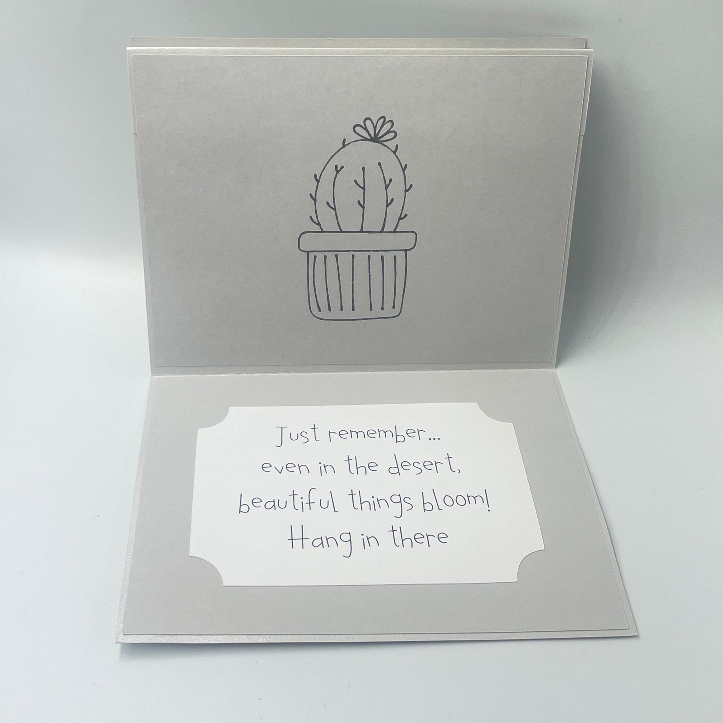 Open card with cactus design and text on a light gray background