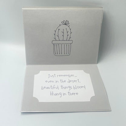 Open card with cactus design and text on a light gray background