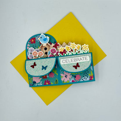 Decorative card with floral design and 'Celebrate' text on a yellow envelope.