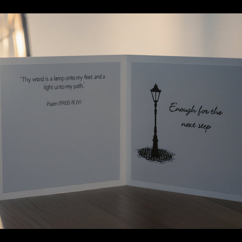 Greeting card with lamp illustration and text next to a lantern on a wooden surface.