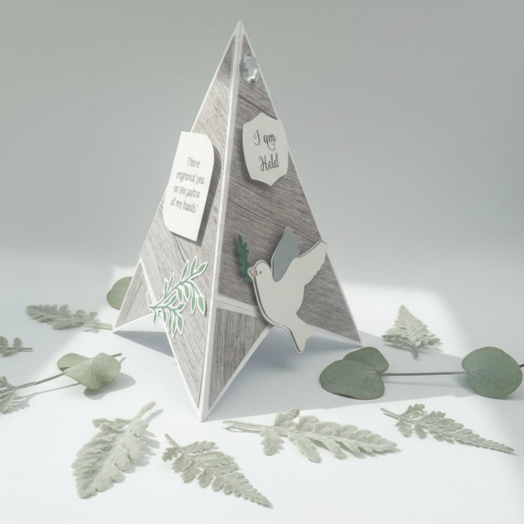 Pyramid-shaped decorative card with dove and leaf designs on a light gray background