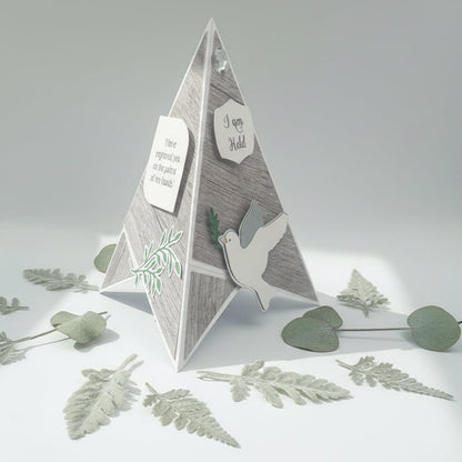 Pyramid-shaped decorative card with dove and leaf designs on a light gray background