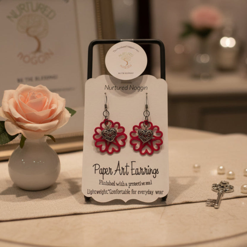 Pair of paper art earrings on a branded card against a gray background