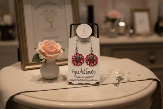 Pair of paper art earrings on a branded card against a gray background