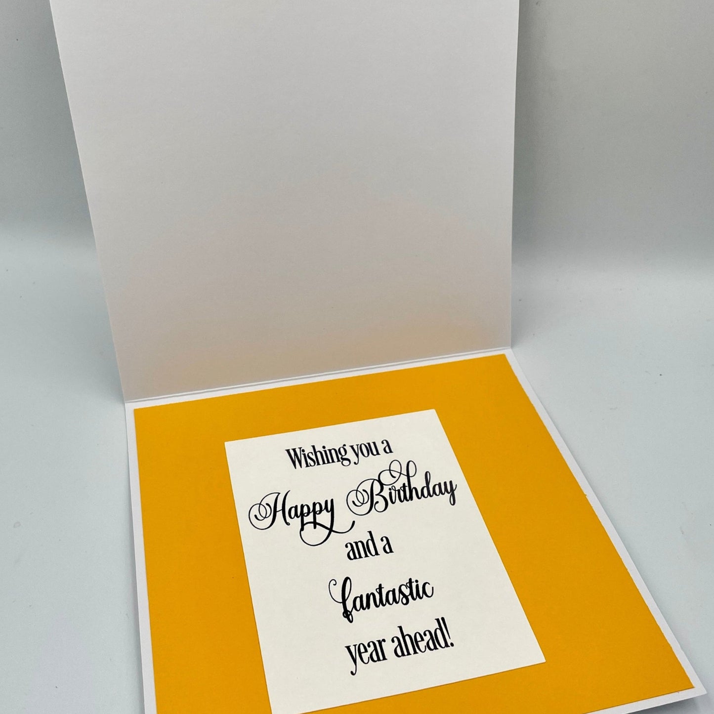 Open birthday card with yellow interior and white exterior on a gray background