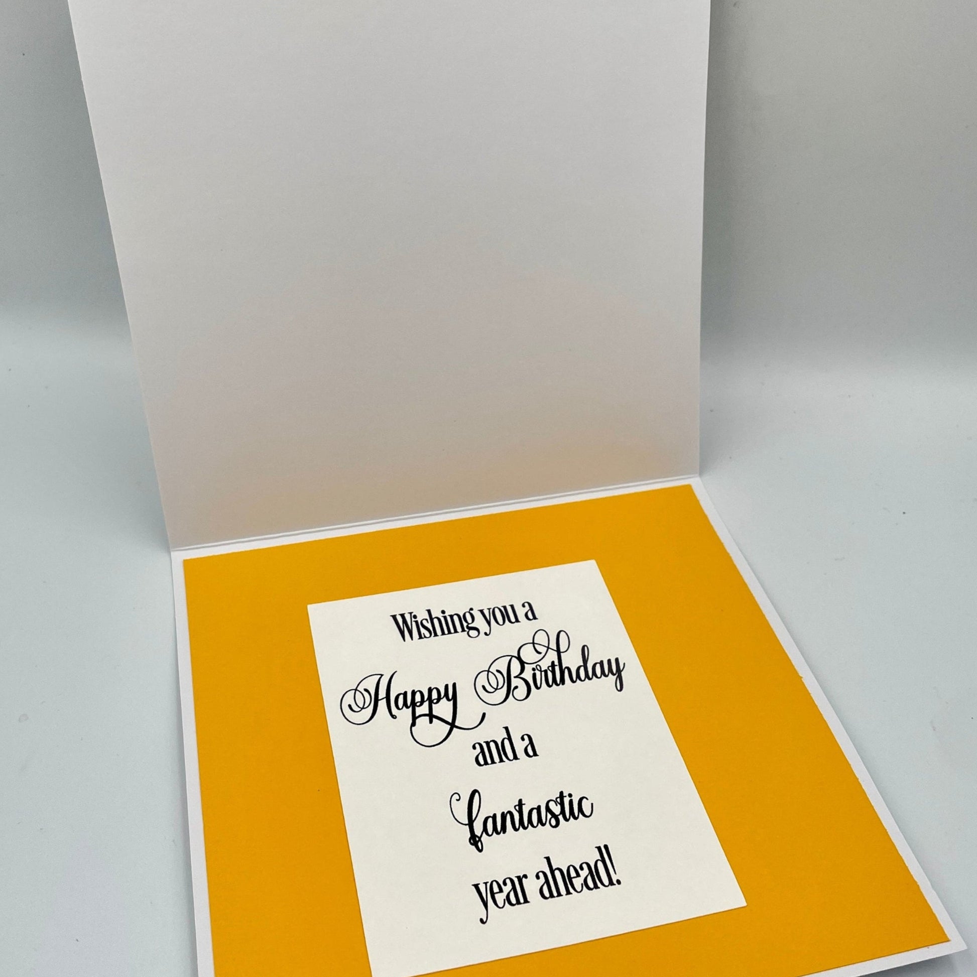 Open birthday card with yellow interior and white exterior on a gray background