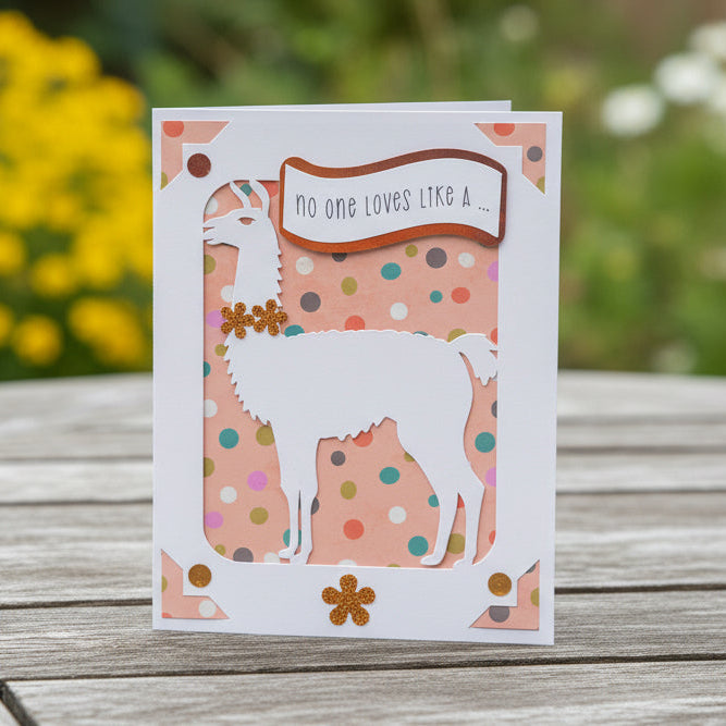 Greeting card with llama design on a wooden surface with flowers in the background
