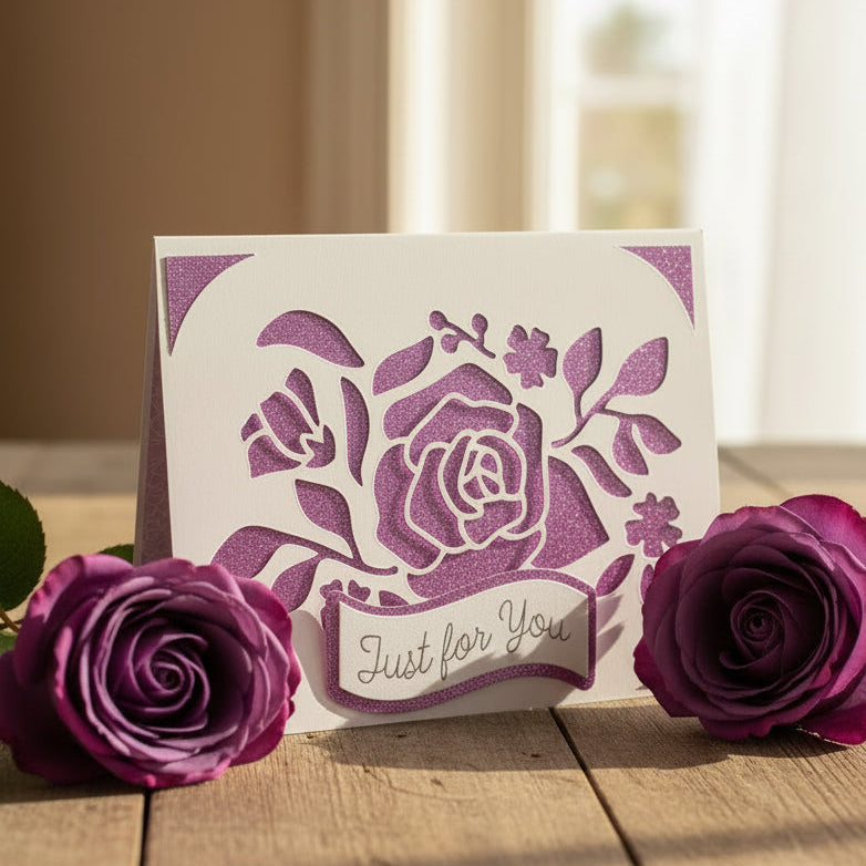Greeting card with floral design and 'Just for You' text, surrounded by purple roses on a wooden surface.