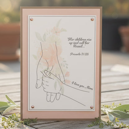 Framed artwork with hands holding hands and text on a wooden surface with greenery.