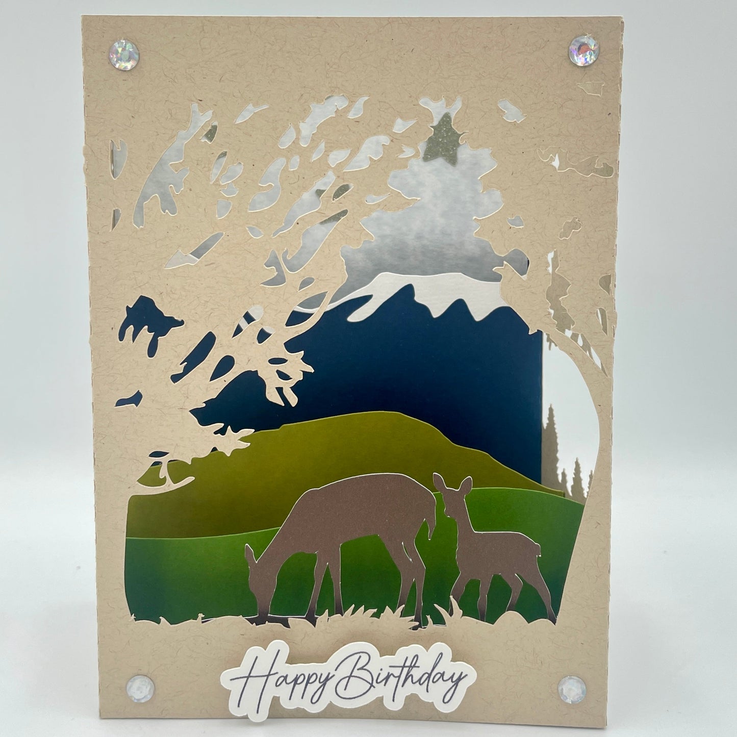 Card with cut-out design of animals in a landscape, featuring 'Happy Birthday' text.