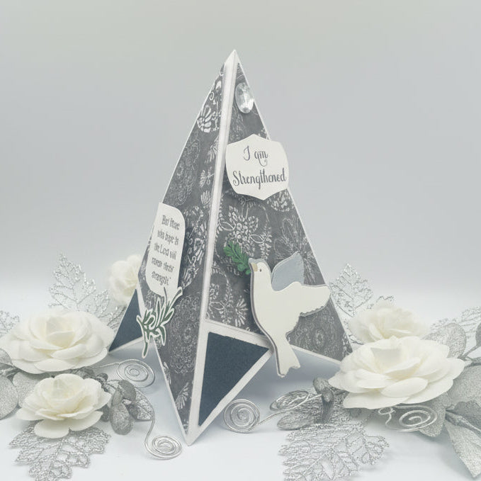 Decorative pyramid with dove and text on a gray background with flowers