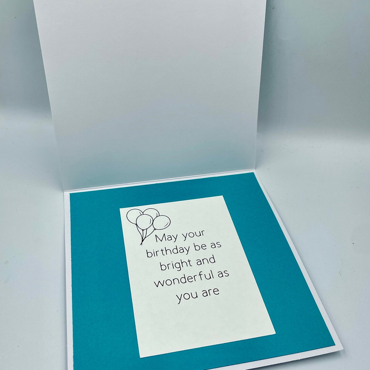 Greeting card with birthday message and balloons on a teal background