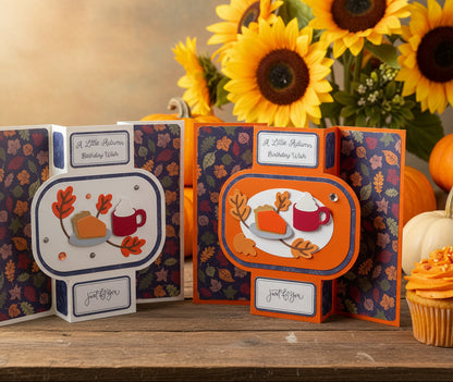 Two handmade pop-up greeting cards displayed side by side on a white surface. The cards feature an autumn theme with colorful fall leaves, a slice of pumpkin pie, and coffee mugs, with text reading 'A Little Autumn Birthday Wish' and 'just for you'.