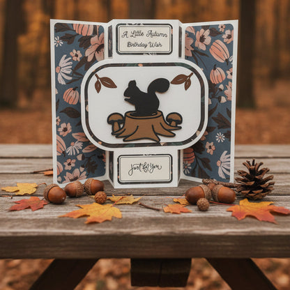 A handmade folding greeting card with a pop-up design. The card features a dark blue floral patterned background with orange and pink autumn-themed illustrations, including pumpkins and leaves.